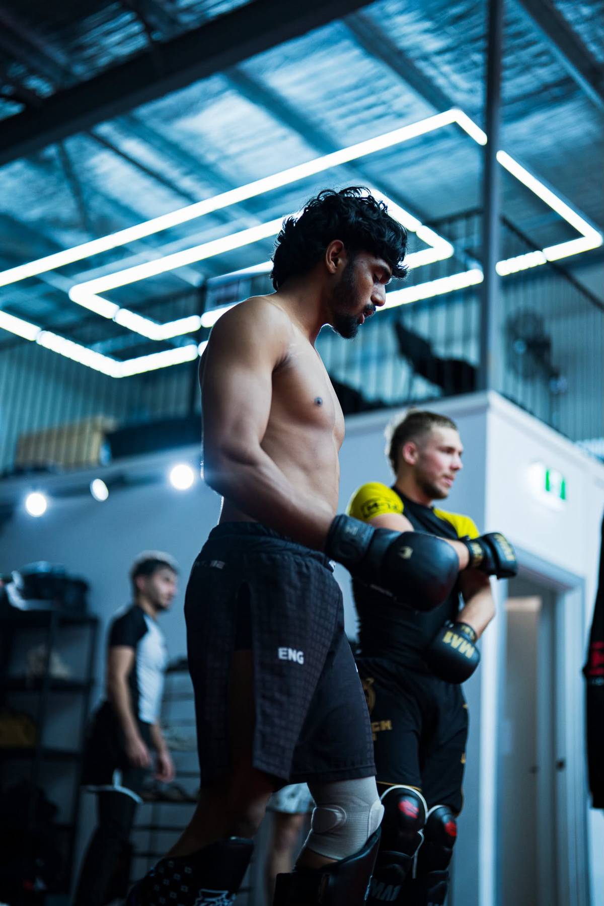Fighter gloving up under gym lights